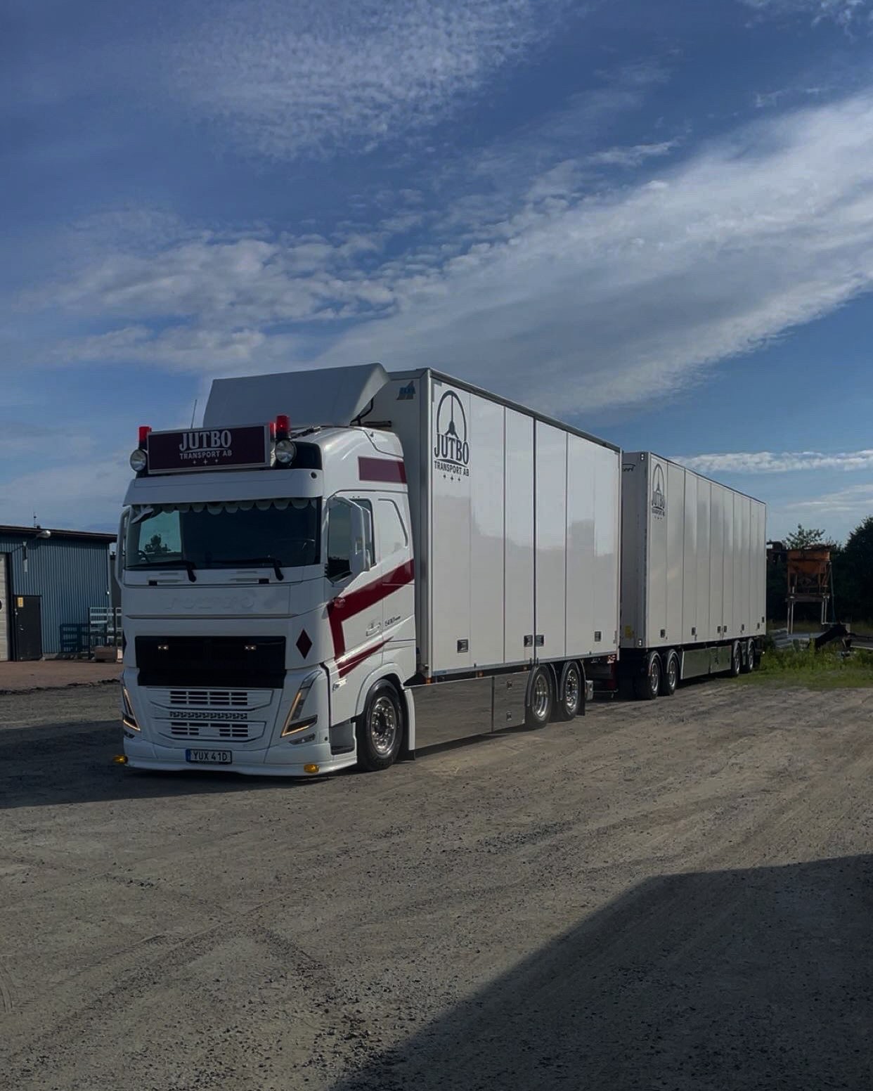Vit Scania med två släp från Jutbo Transport på en grusplan
